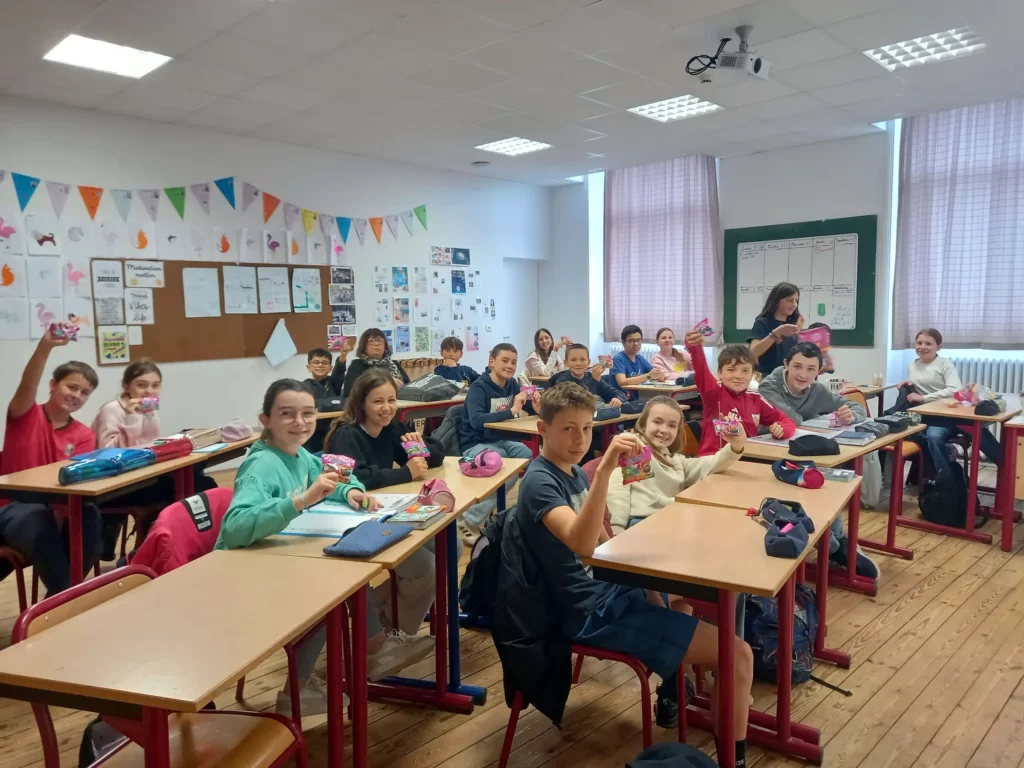 Élèves de 6ème en classe, assis par groupes autour de tables.