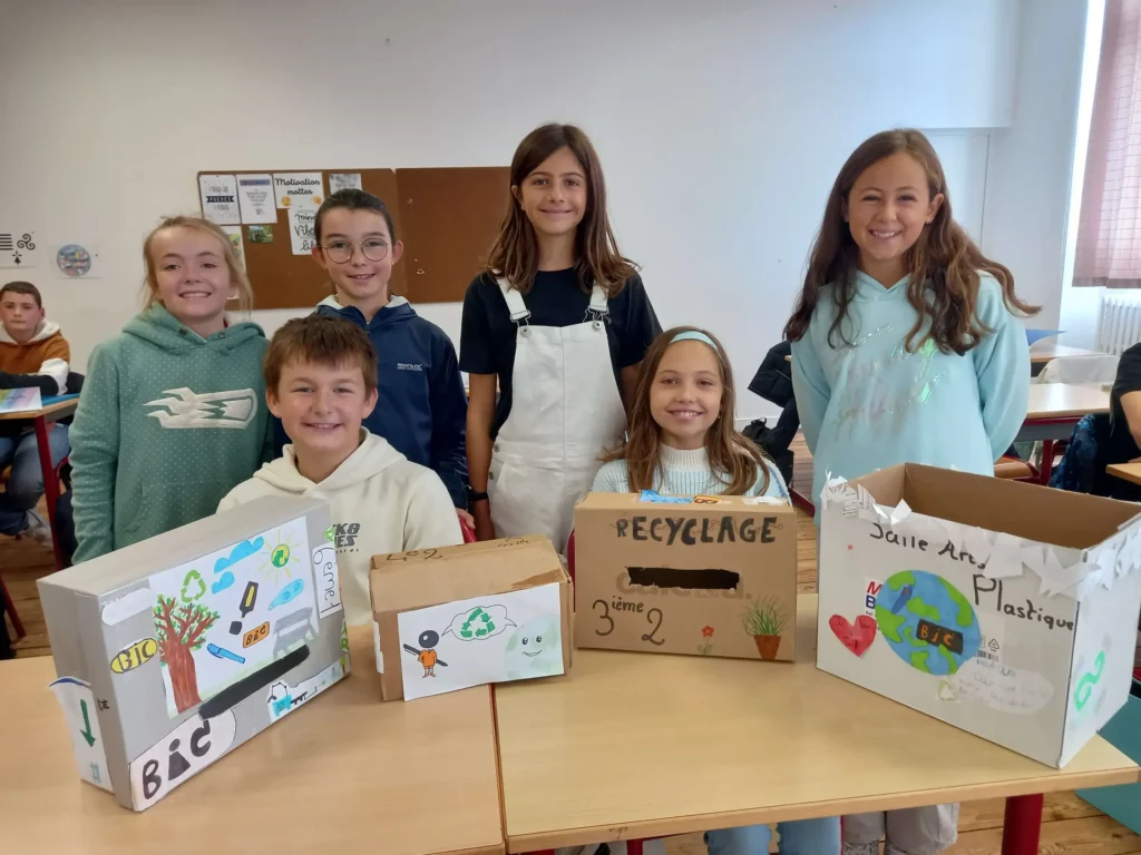 Groupe d'élèves tenant des boîtes de crayons collectés pour une action solidaire.