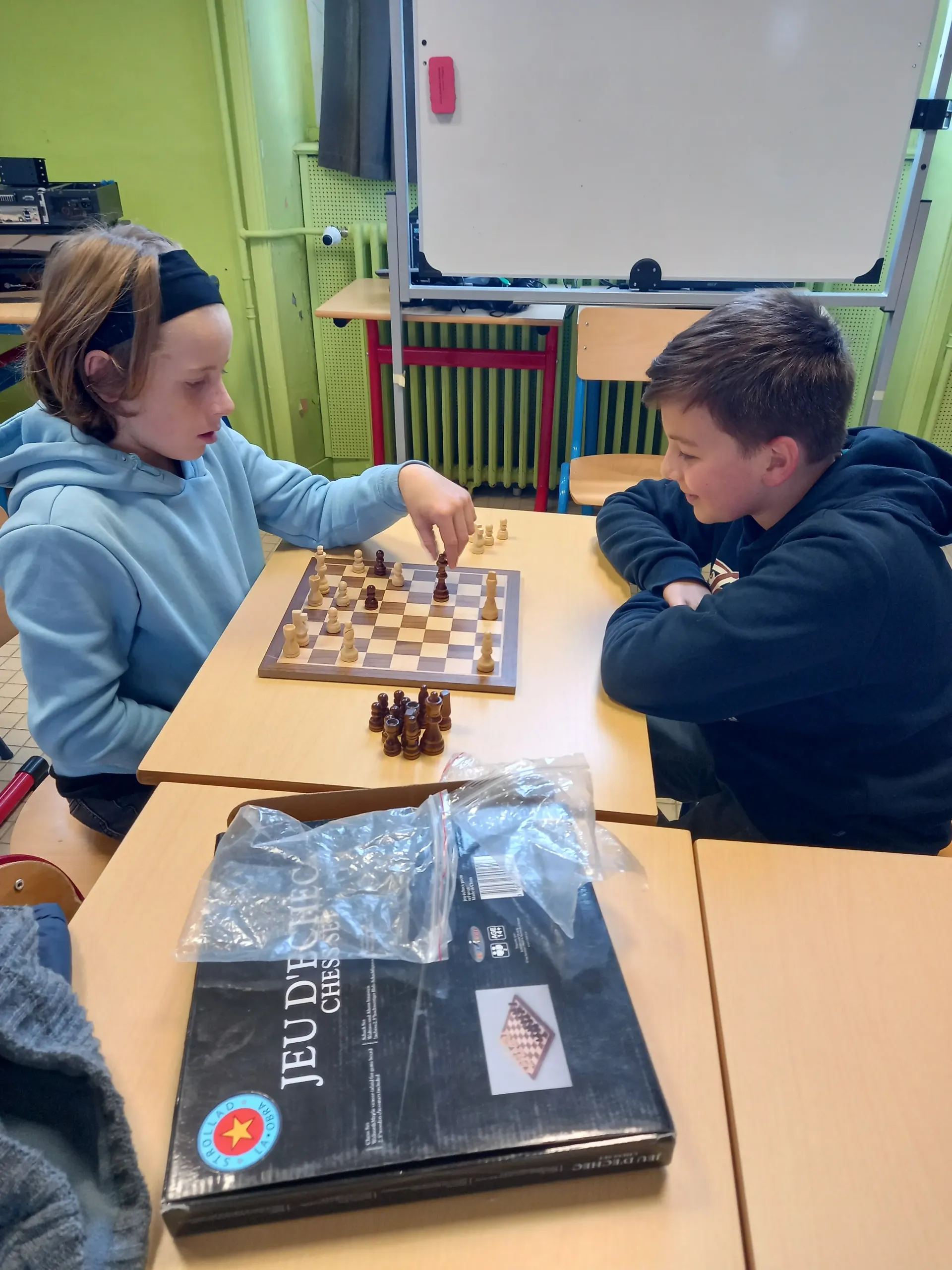 Deux élèves concentrés face à un échiquier lors d'une partie d'échecs.