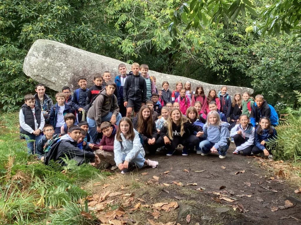 Grand groupe d'élèves et d'adultes en photo de groupe à l'extérieur.