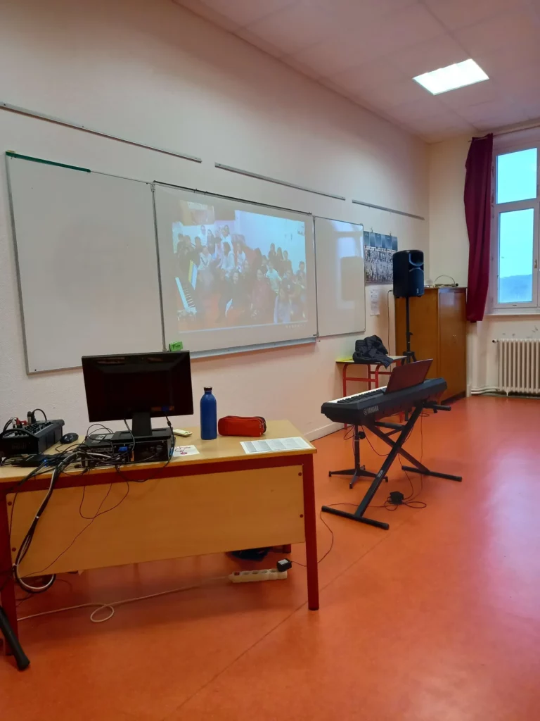 Salle de musique avec pupitres, piano et vidéoprojecteur allumé sur le mur.