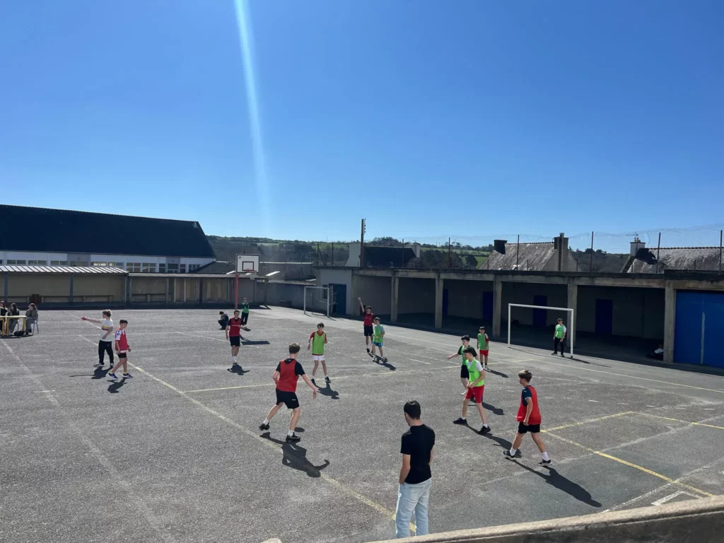 Vue de la cour du collège pendant un tournoi de football, élèves en jeu.