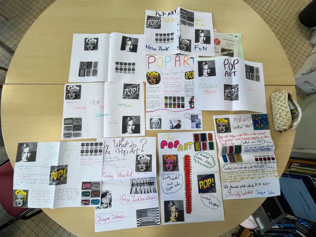 Affiches réalisées par les élèves de 3ᵉ sur le pop art, présentées sur une table au Collège La Mennais Cap Sizun.