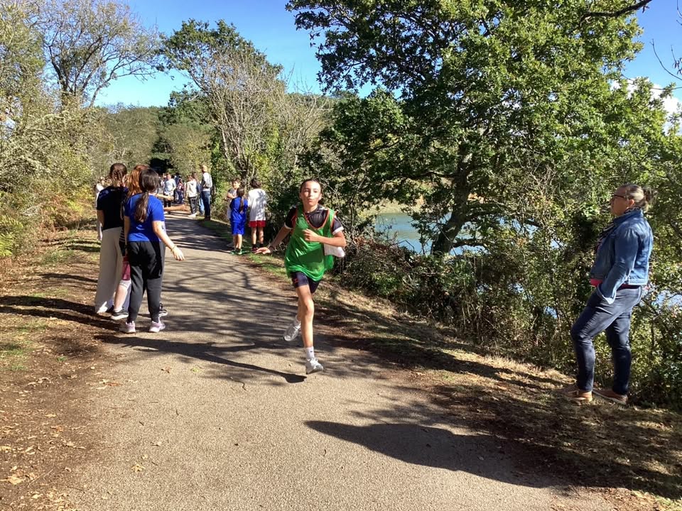 Une élève court sur un chemin bordé d'arbres lors du cross solidaire