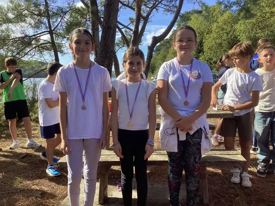 Trois jeunes élèves médaillées posant ensemble après le cross solidaire