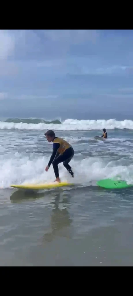 Un jeune surfeur du Collège La Mennais Cap Sizun prend une vague sur sa planche jaune à la Baie des Trépassés.