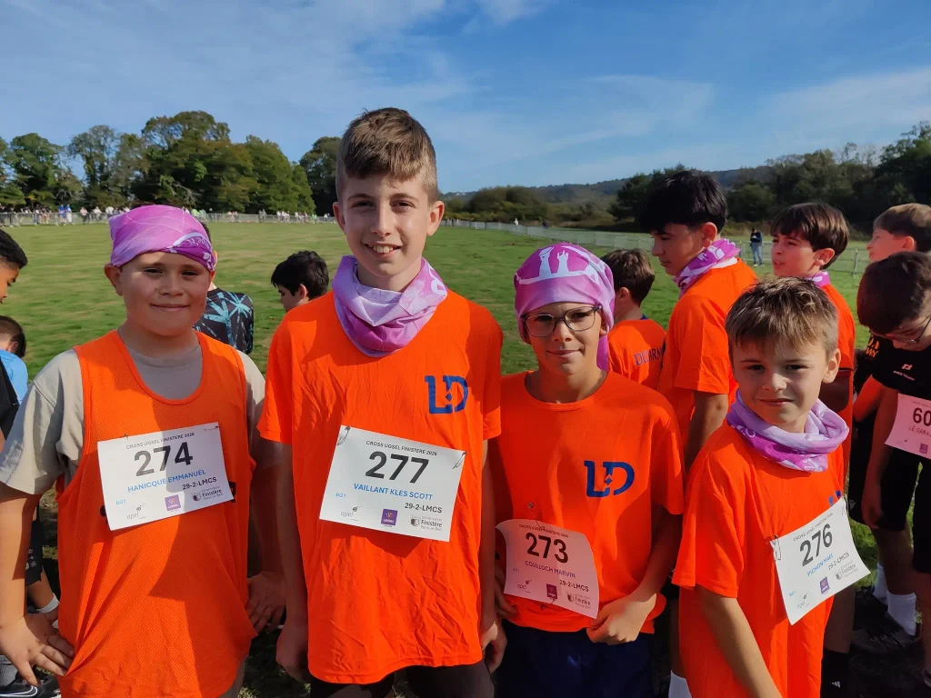 Quatre élèves en maillots orange posent ensemble avant ou après leur participation au cross départemental UGSEL.