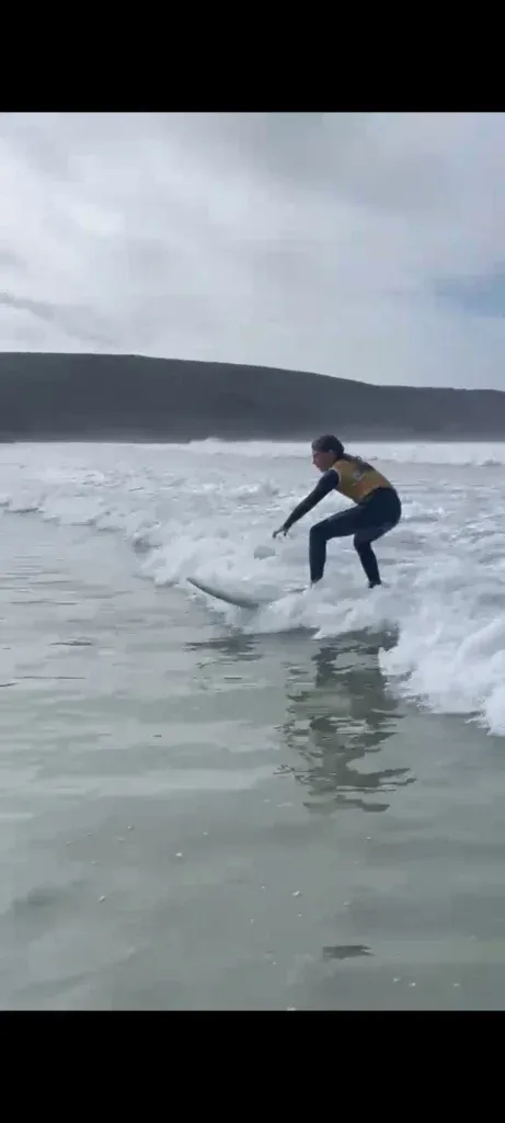 Une jeune surfeuse en combinaison évolue sur une vague lors d'un entraînement à la Baie des Trépassés.